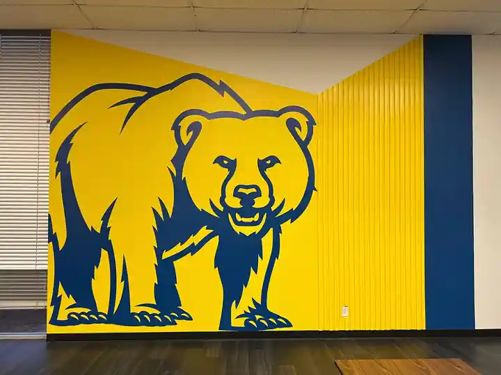 A gold Brownsboro Bear painted across a navy and gold wall