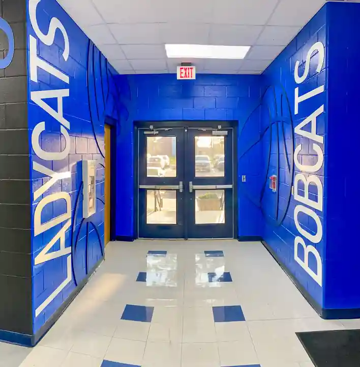 A royal-blue school entry hall lettered Ladycats and Bobcats