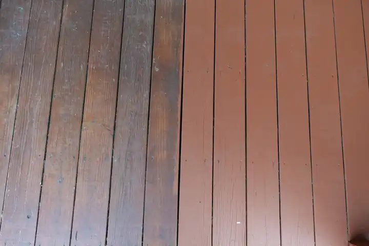 Deck boards partway through a refinish: worn, faded boards on the left and freshly coated reddish-brown boards on the right