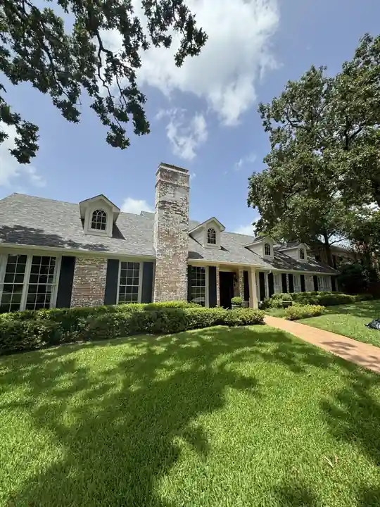 A brick ranch home with dormers and freshly painted shutters and trim