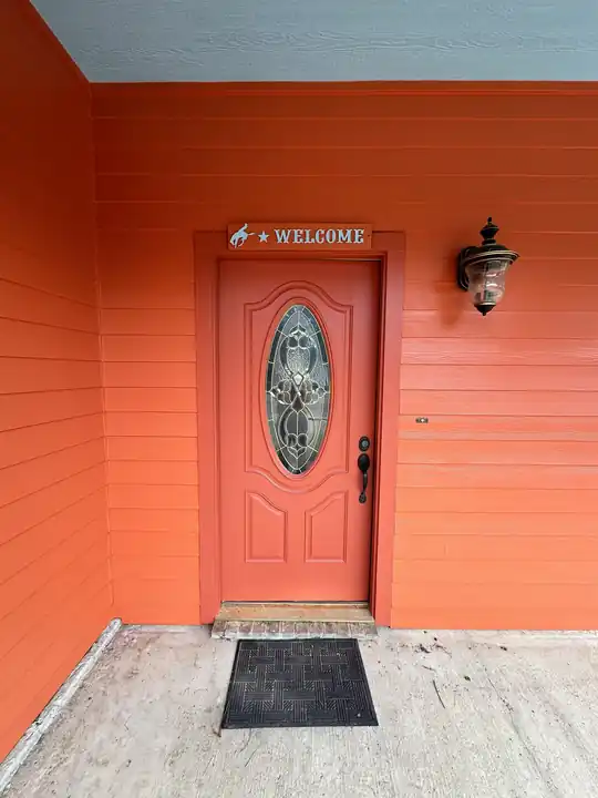 A house with coral siding and a coral door with an oval glass panel