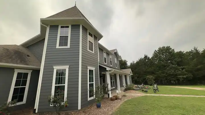 A gray-sided house with a turret and white trim
