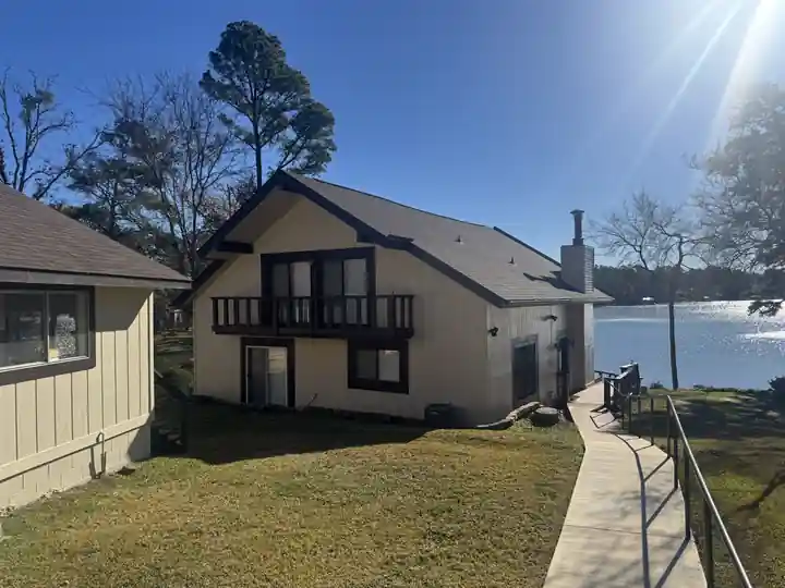 A lake house with cream siding and dark trim in low sun