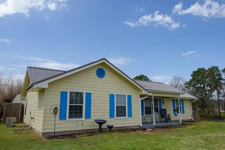 A yellow house with blue shutters and a metal roof