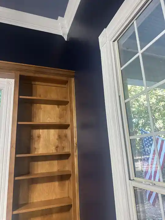 A navy room with white trim and a stained bookcase