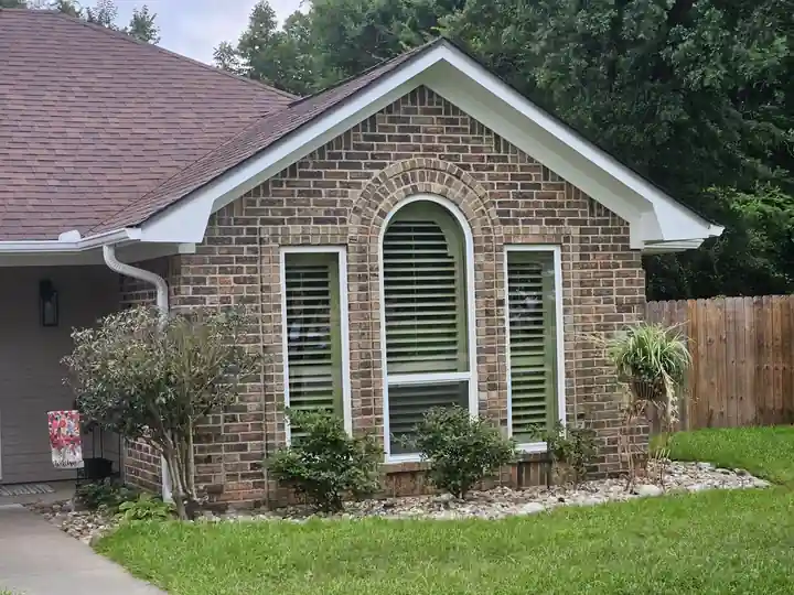A brick home with an arched window and white trim