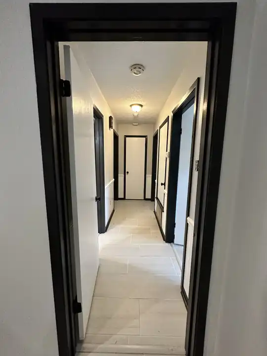 A hallway with white walls and black door casings