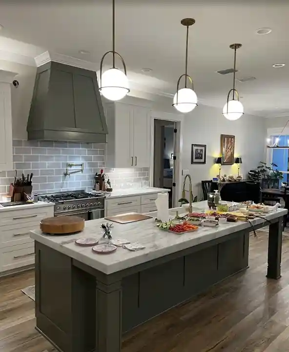 Painted kitchen island and custom range hood against lighter cabinets