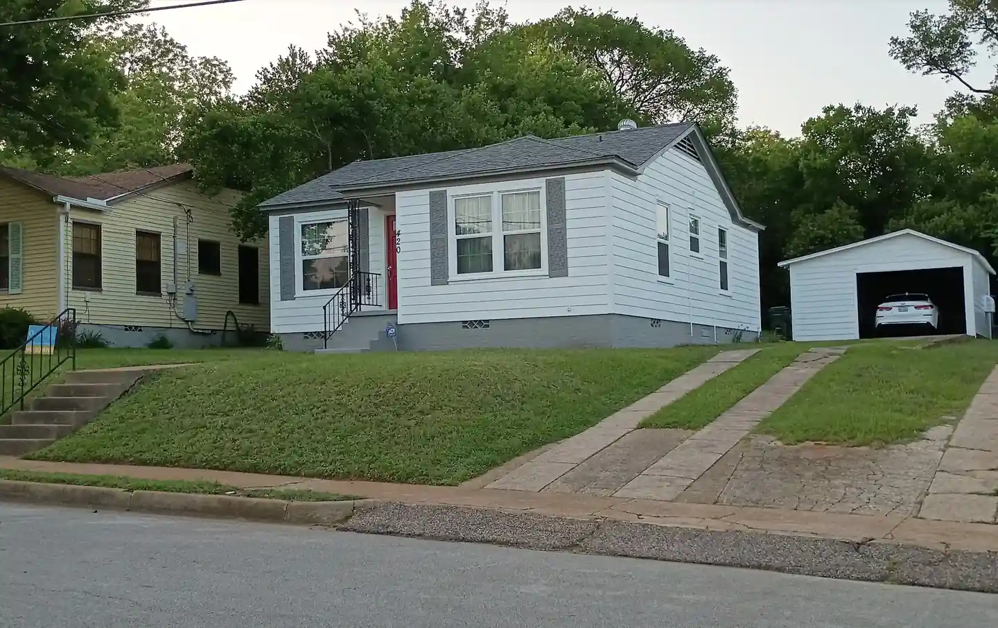The Tyler cottage Quality Coats repainted after another company skipped the prep: white siding, gray shutters, red front door
