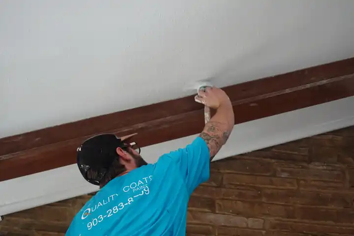 Painter cutting in a ceiling beam over a brick wall