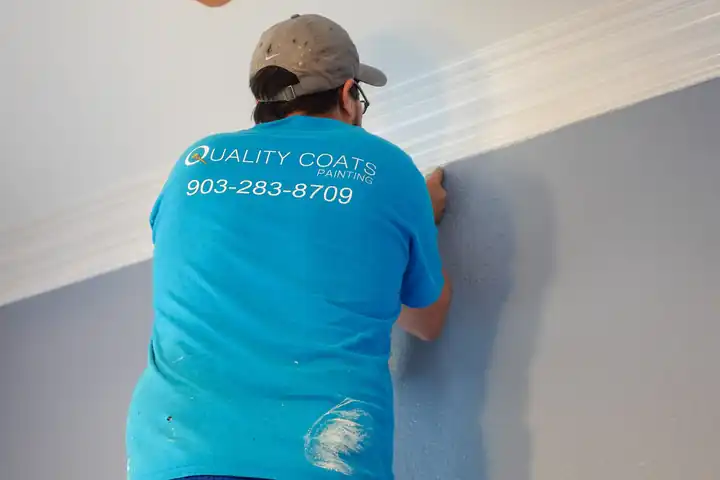 A Quality Coats painter working a crisp trim line along a wall